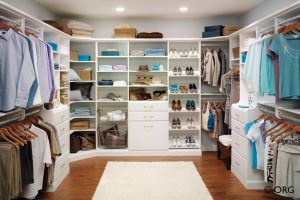 walk in closet with open white shelving and a drawer base